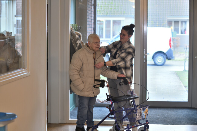 Zorgmanager Anouk helpt cliënt met het aandoen van een jas.